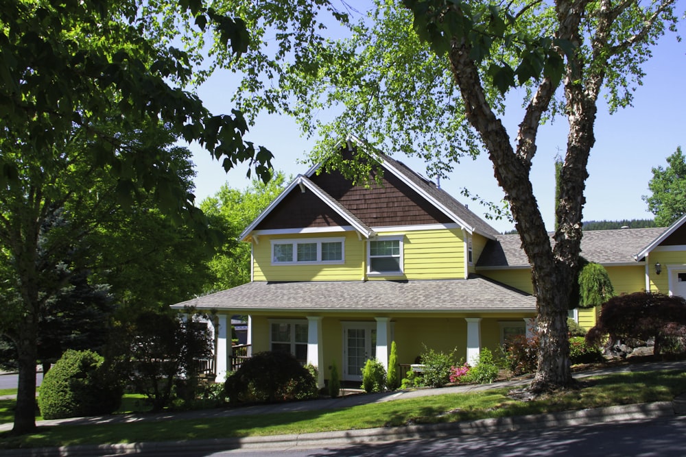 una casa gialla con un albero di fronte