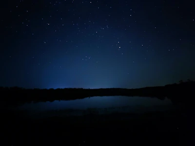 A serene night sky filled with twinkling stars over a calm ocean reflecting the constellations.