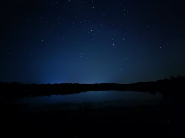 A serene night sky filled with twinkling stars over a calm horizon.