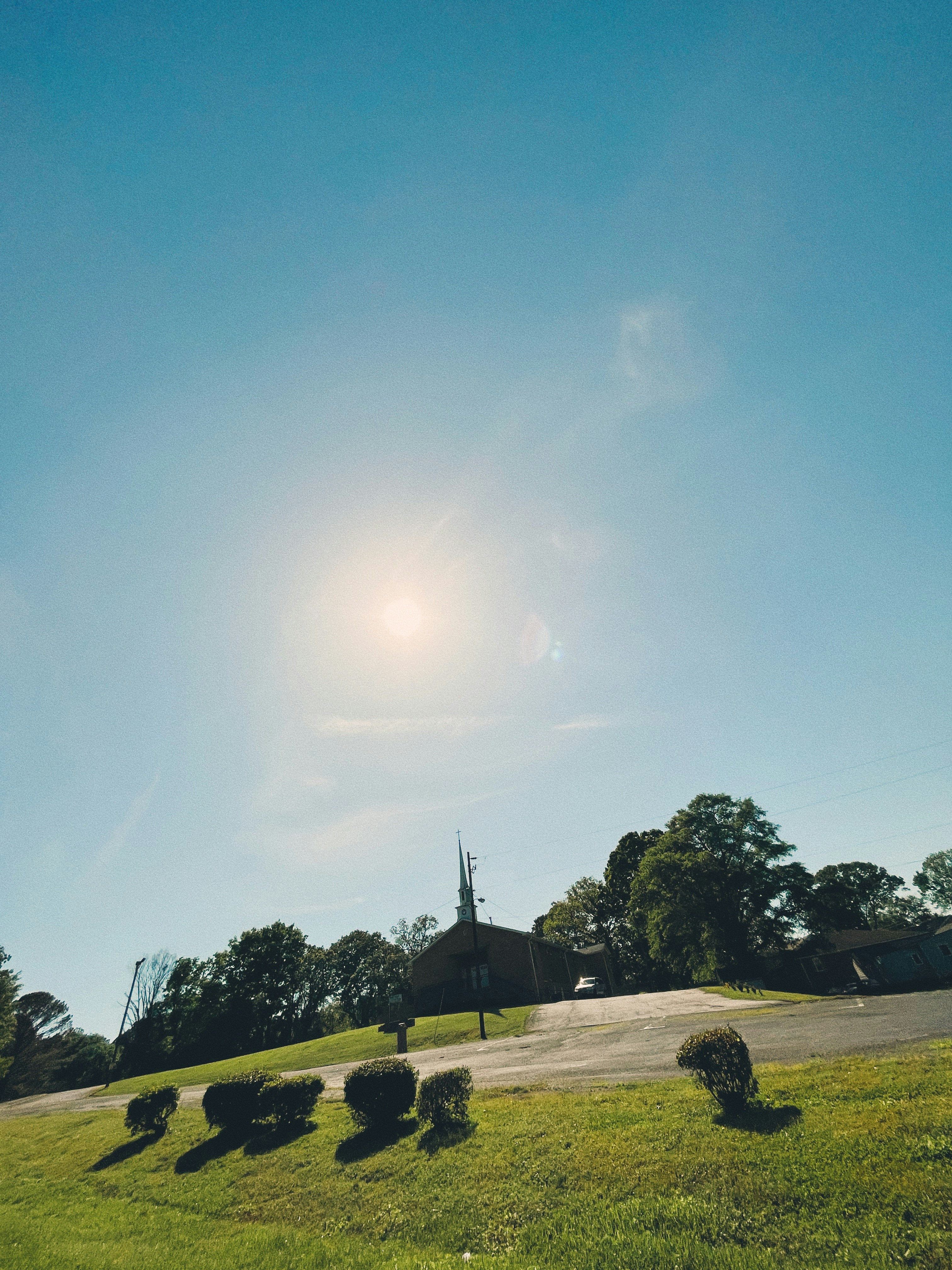 the sun is shining over a grassy hill