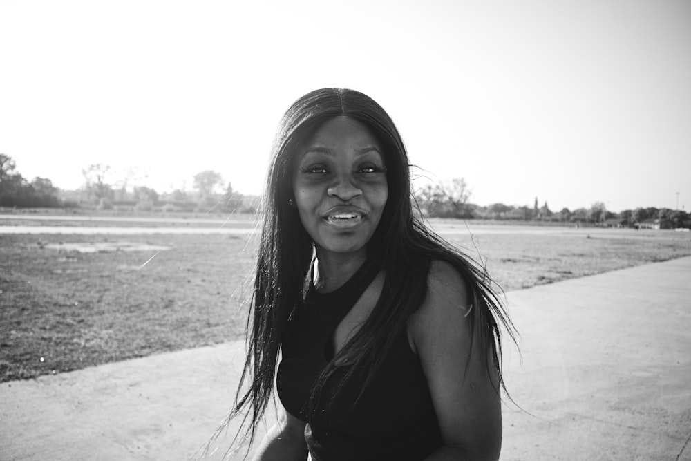 a woman in a black dress standing on a sidewalk