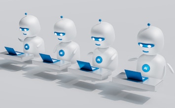 Four small, white robot figures are sitting in a row, each with a laptop in front of them. They have round bodies and blue accents, with 'AI' displayed on their chests. The background is minimal and light gray, emphasizing the robots and their computers.