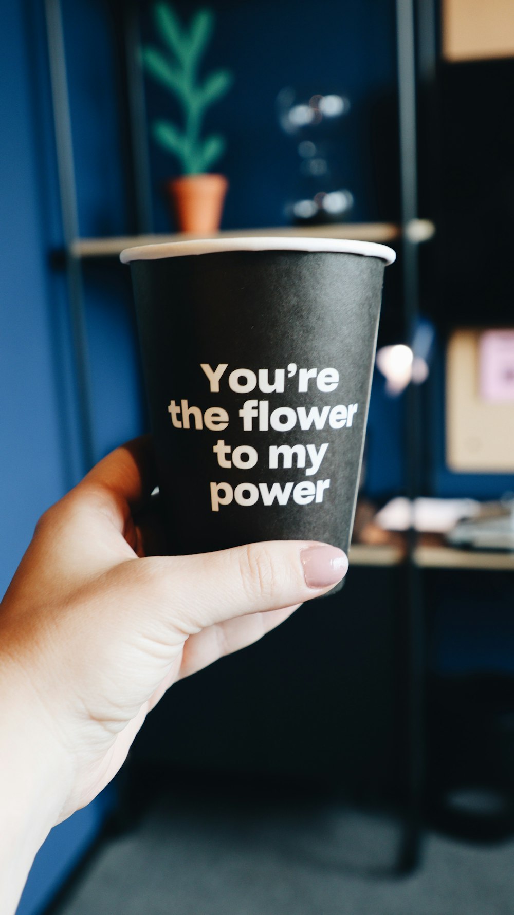 a person holding a cup with the words you're the flower to my power
