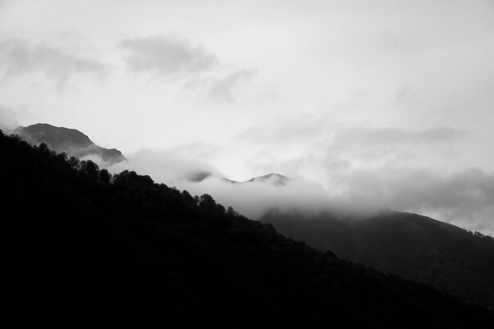 a black and white photo of a mountain covered in clouds