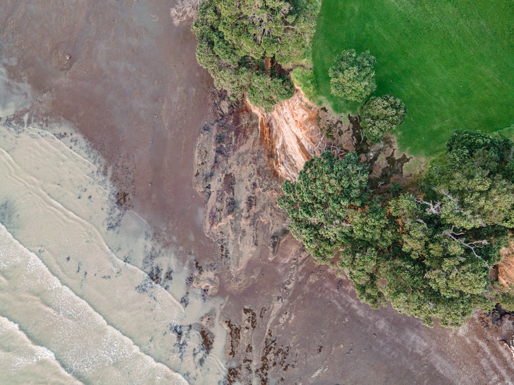 an aerial view of a grassy area next to a body of water