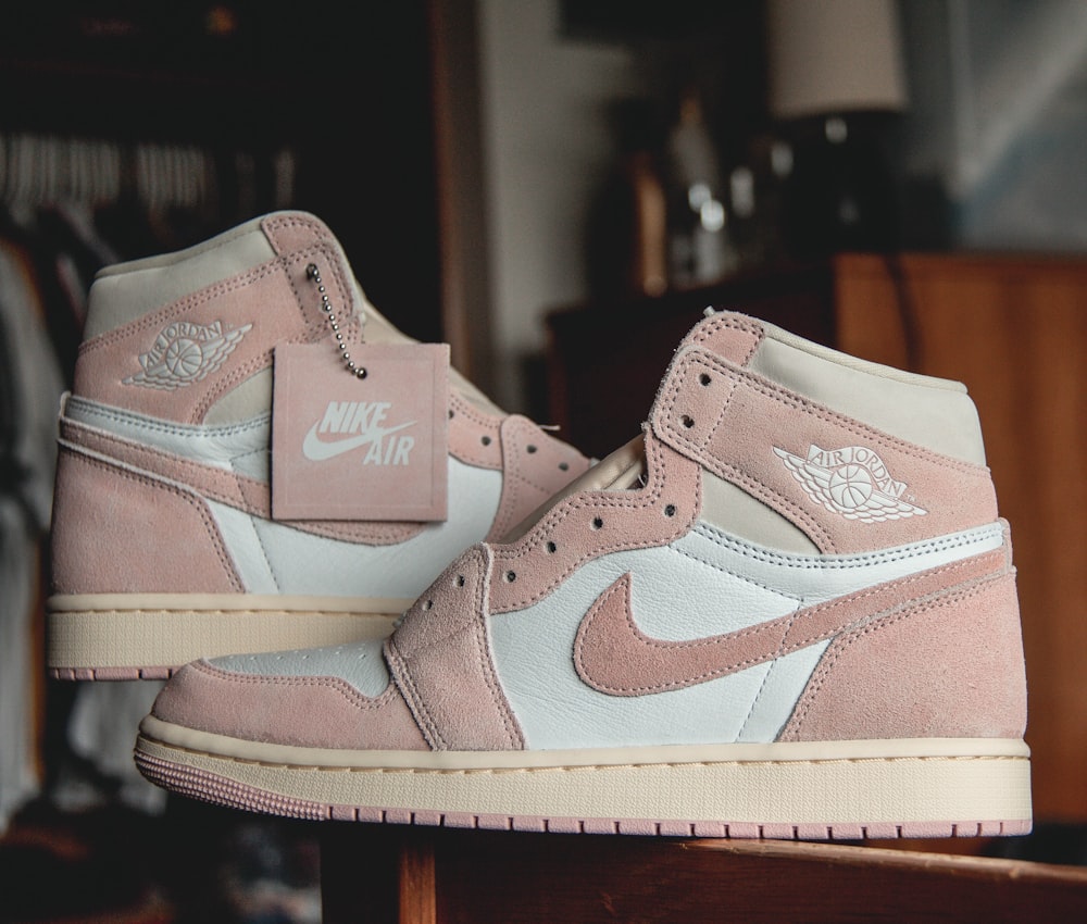 a pair of pink and white sneakers sitting on top of a wooden table