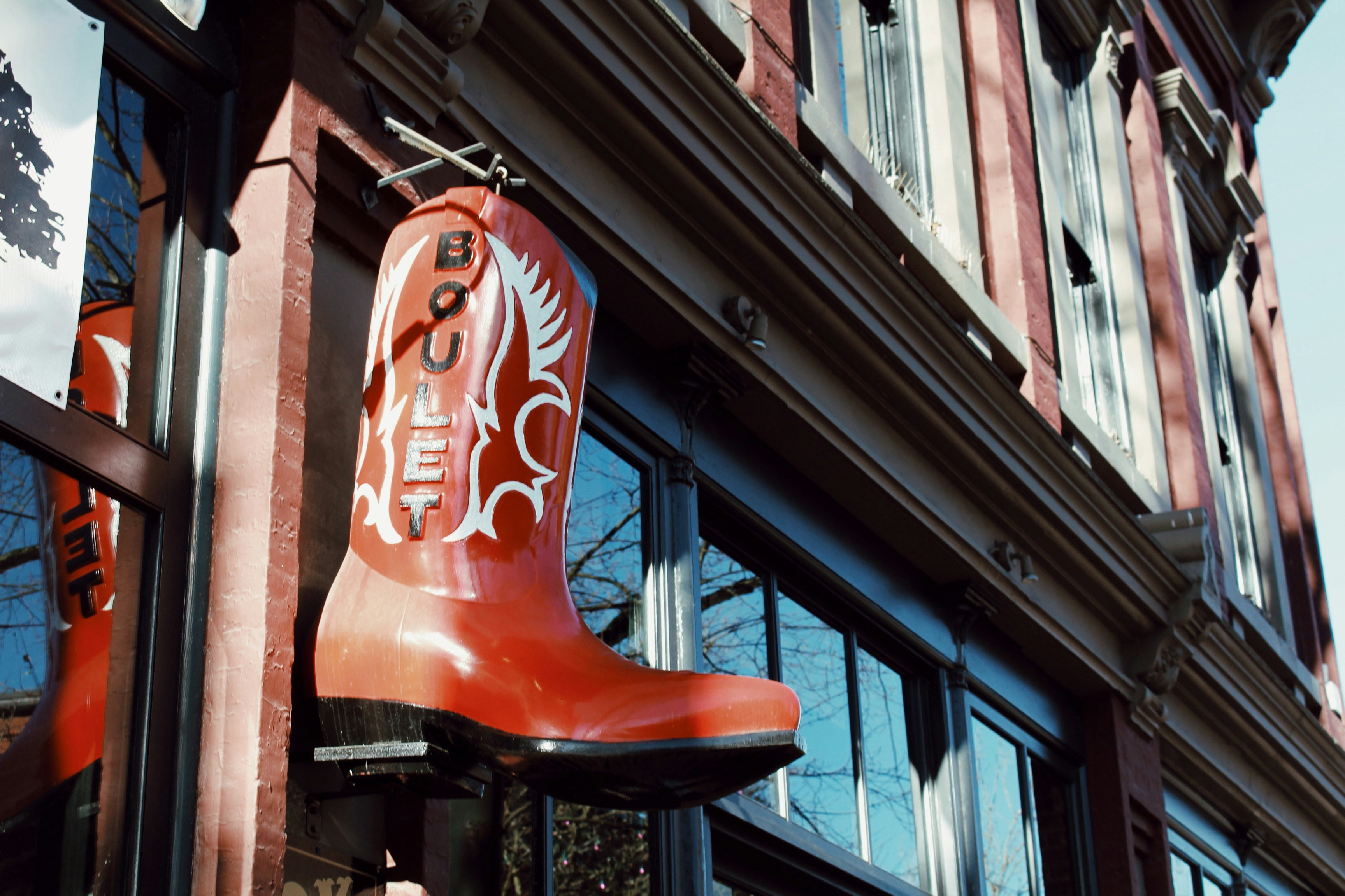 a tall red boot hanging from the side of a building, 