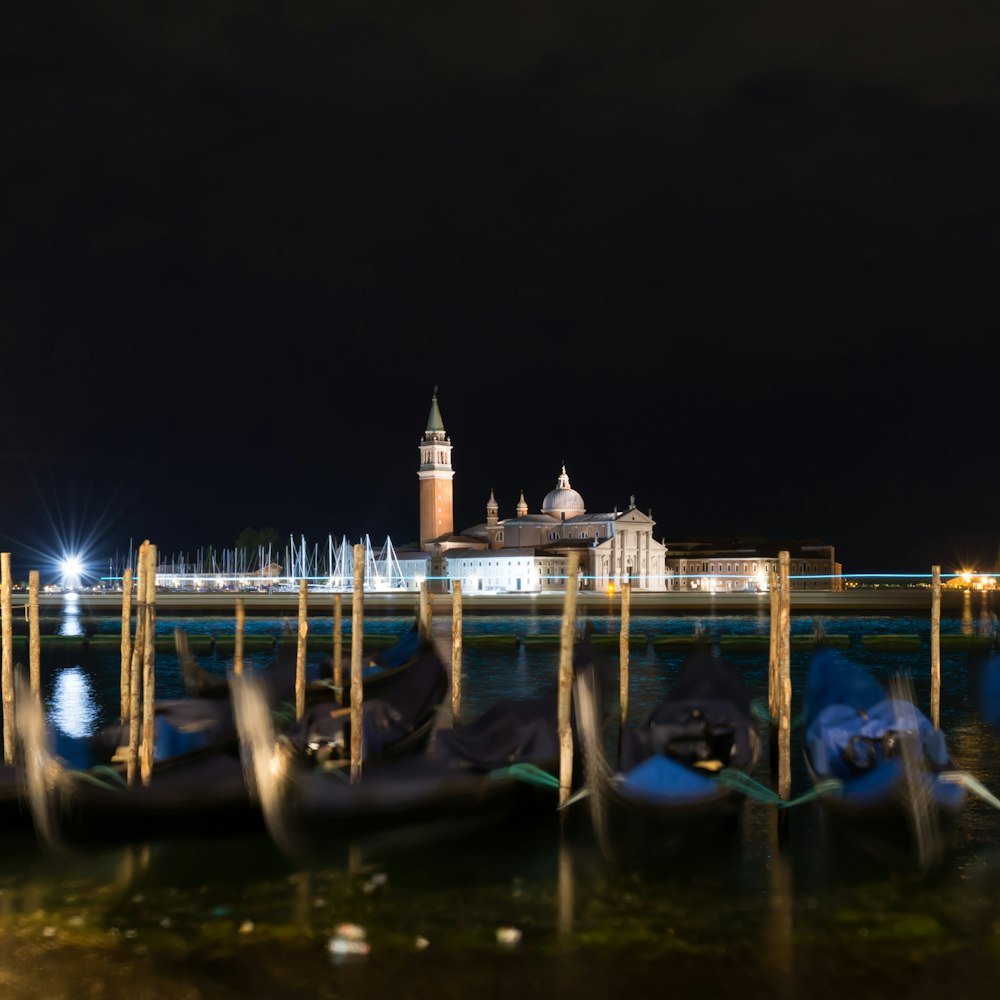 a row of gondolas sitting next to a pier at night