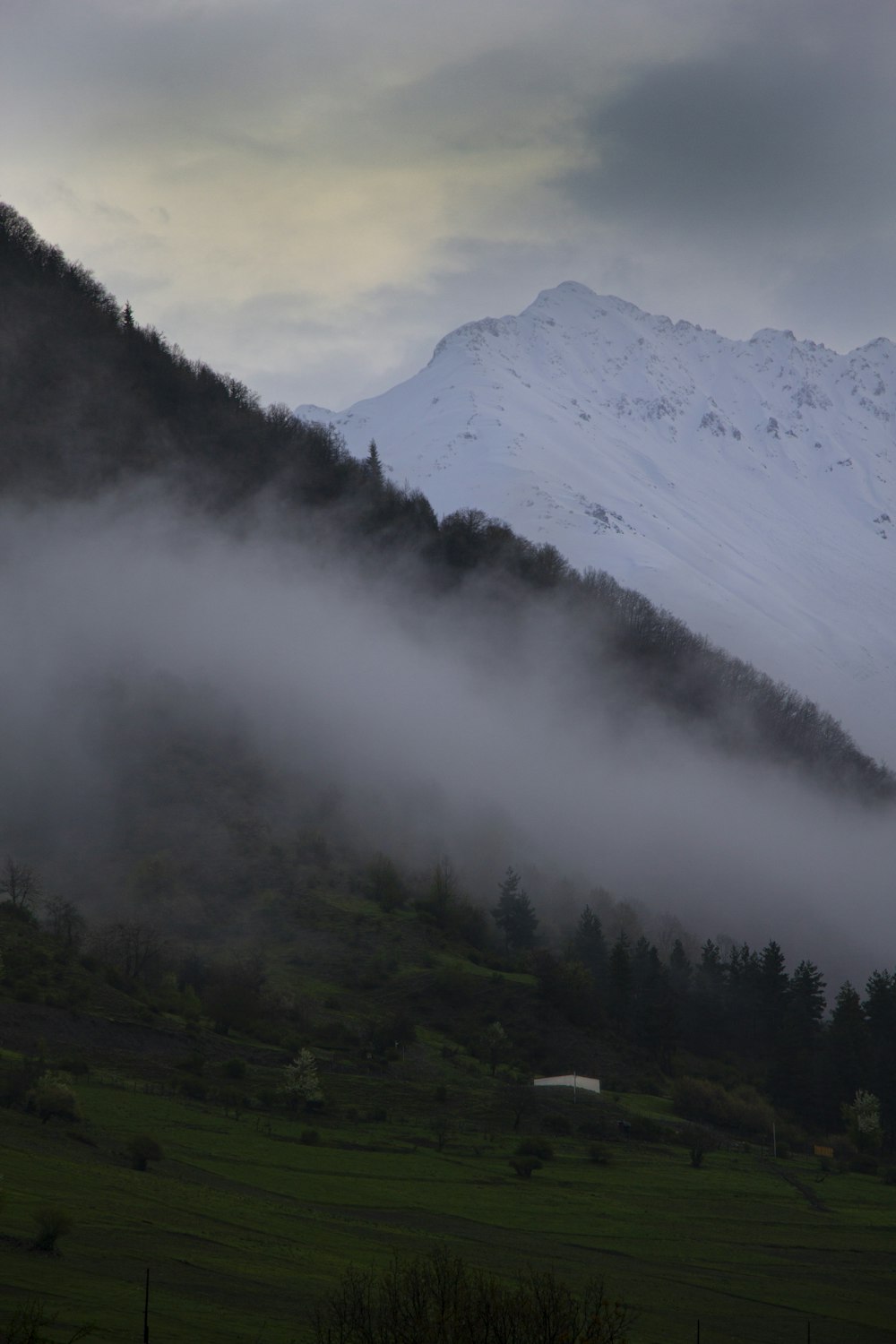 a mountain covered in fog with a house in the foreground