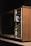 A vintage television set with wood paneling and various manual adjustment knobs and sliders for volume, contrast, brightness, and vertical hold on the side.