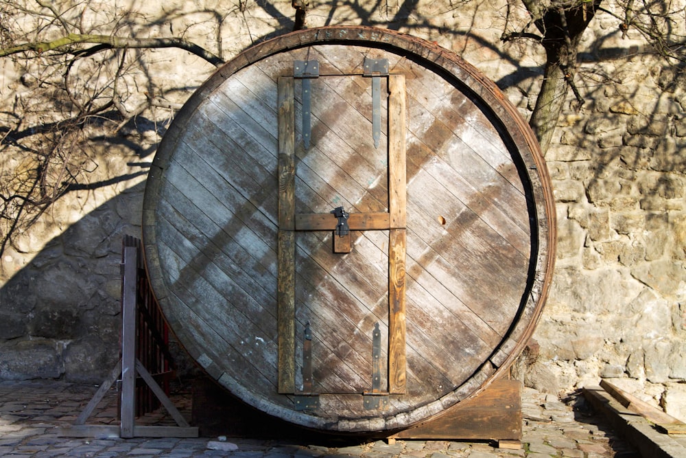 a large wooden barrel sitting in front of a stone wall