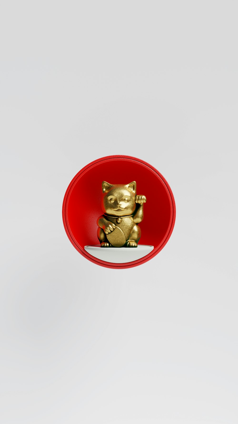 Una figura de gato dorado sentada en un cuenco rojo