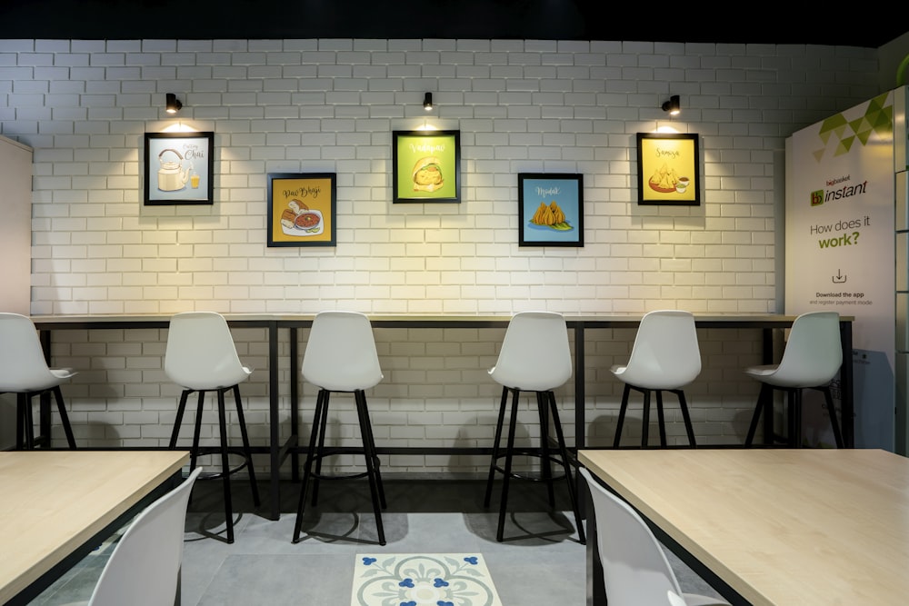 a row of white chairs sitting in front of a white brick wall