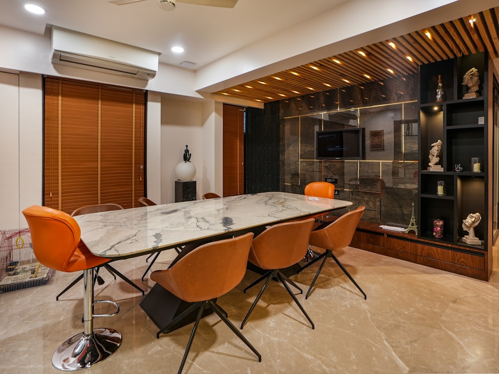 a dining room with a marble table and orange chairs