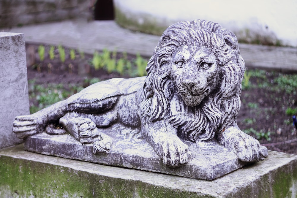 Una estatua de un león acostado encima de un bloque de cemento