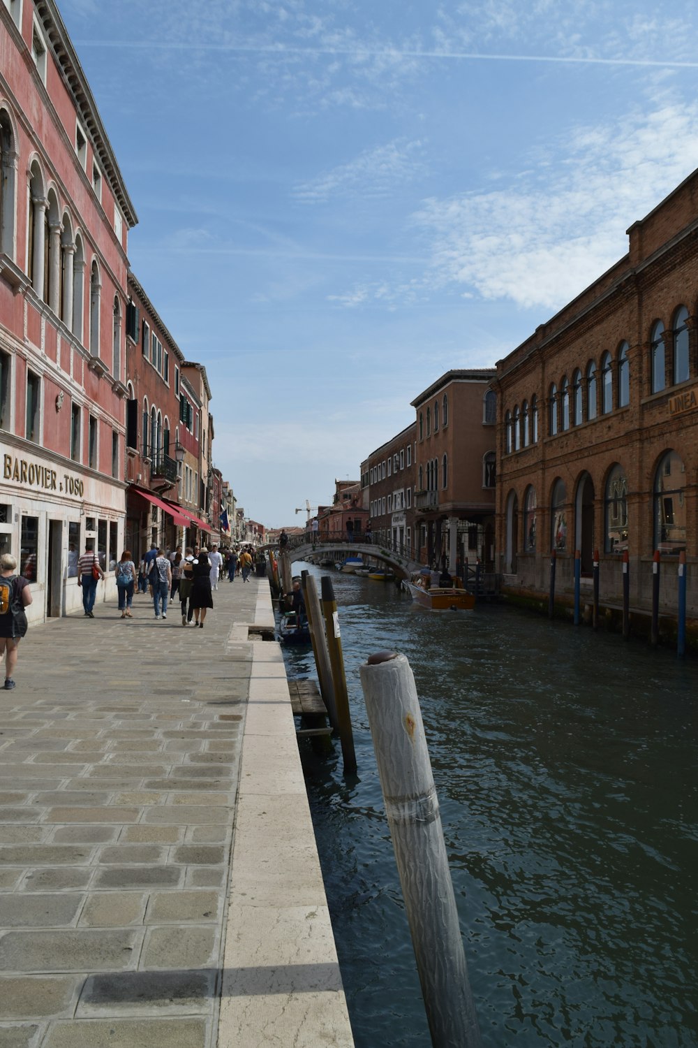 people walking on a sidewalk next to a body of water