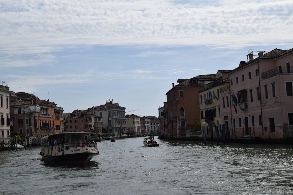 a boat traveling down a river next to tall buildings