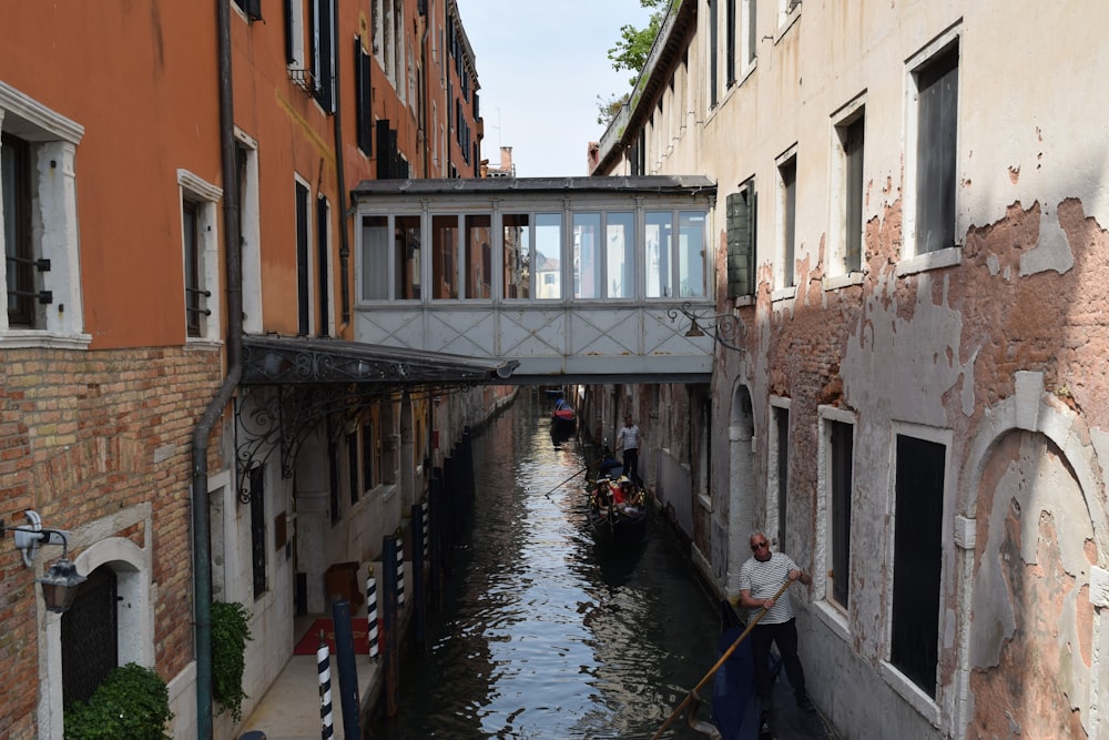 a man riding a boat down a canal under a bridge