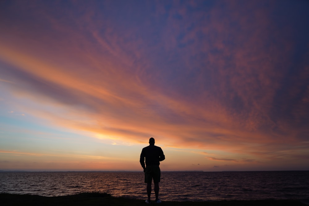 a man standing on top of a beach next to the ocean