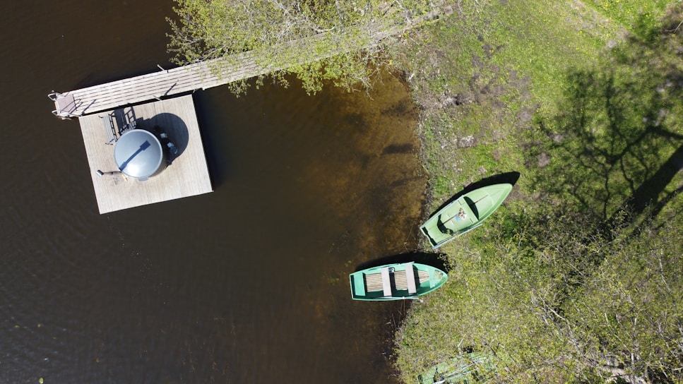 two green canoes sitting on a dock next to a body of water