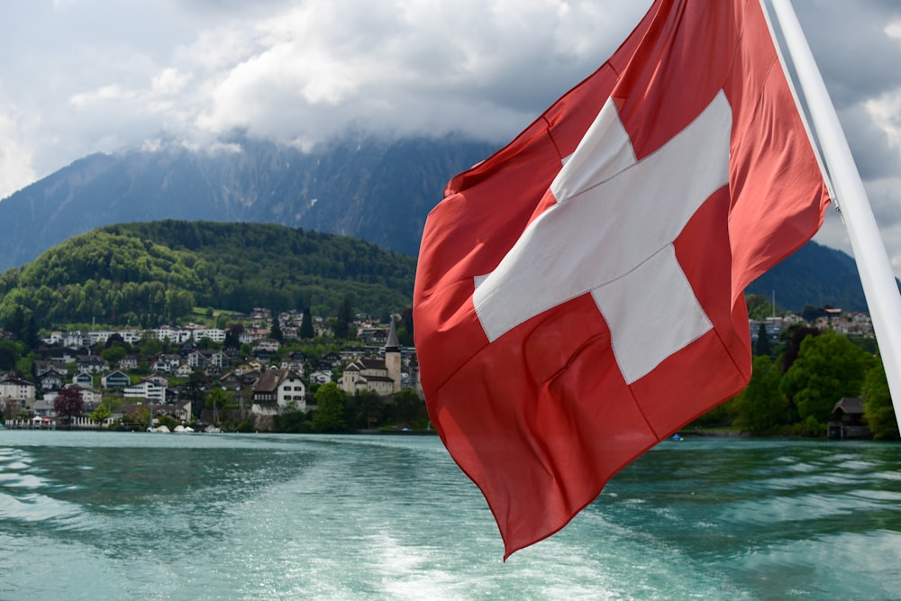 a red and white flag flying over a body of water