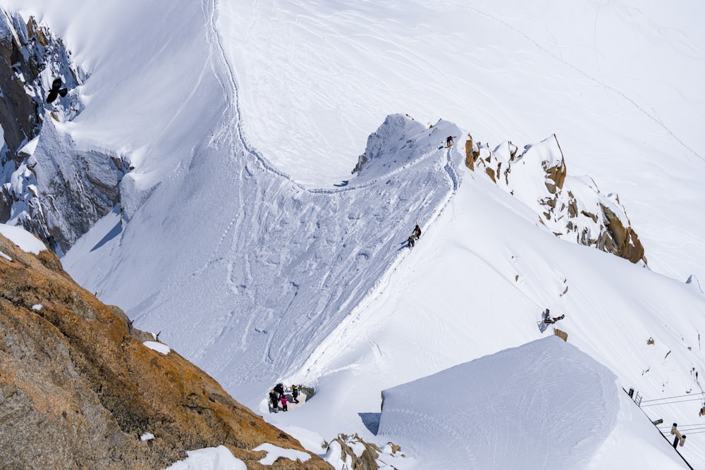 a group of people climbing up the side of a snow covered mountain