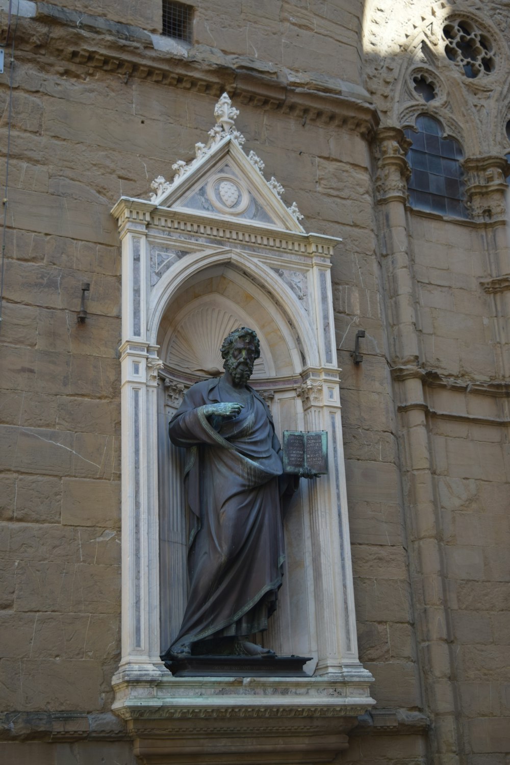 a statue of a man holding a cross in front of a building