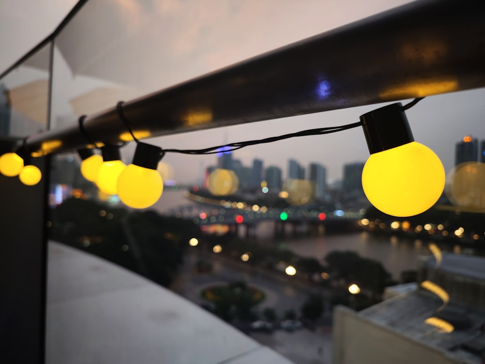 yellow lights are hanging from a balcony overlooking a city