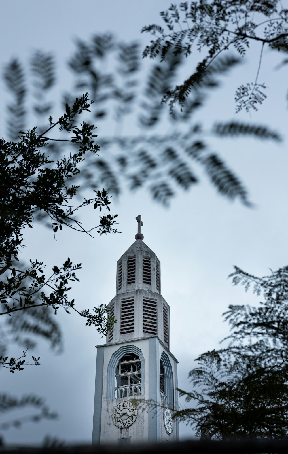 a tall white clock tower with a clock on each of it's sides