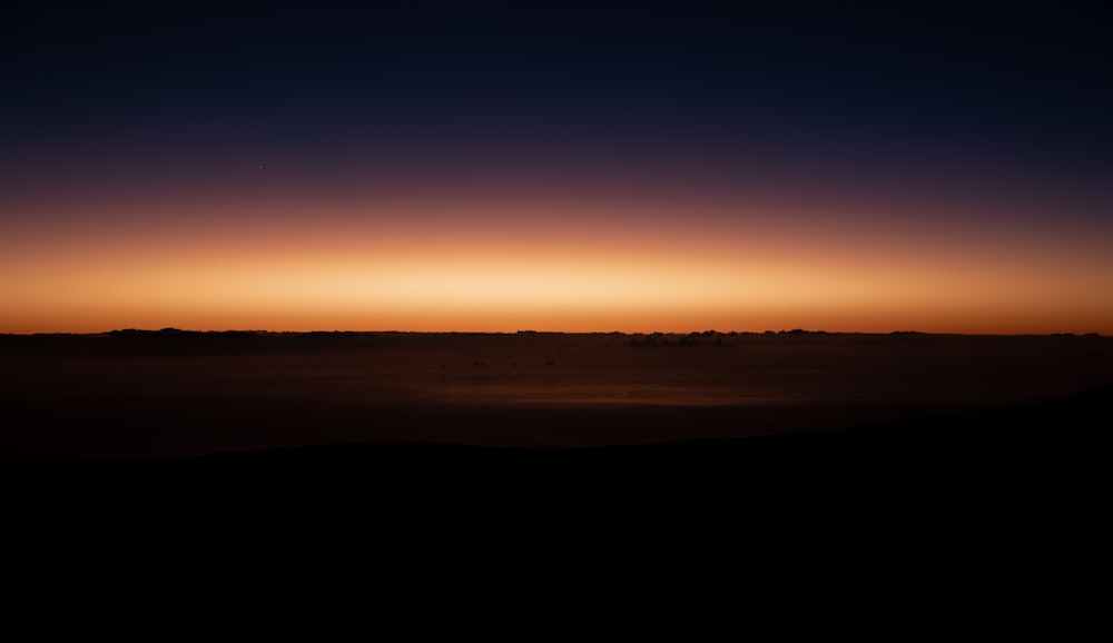 the sun is setting over the horizon of a desert