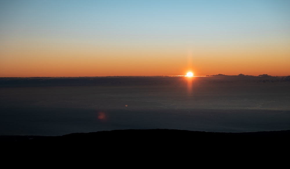 the sun is setting over the horizon of a large body of water