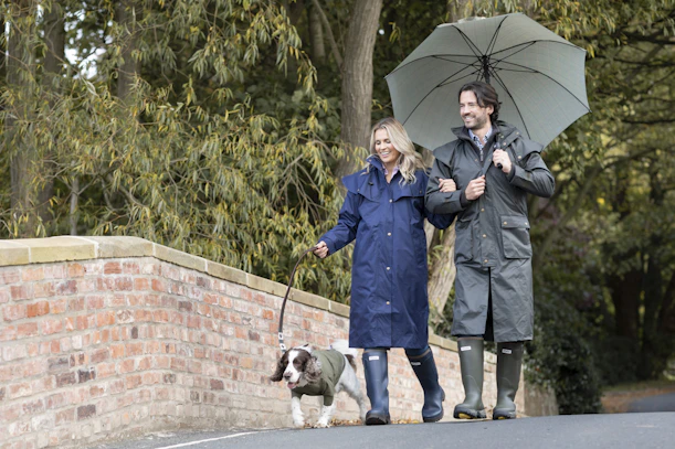 a man and woman walking a dog with an umbrella