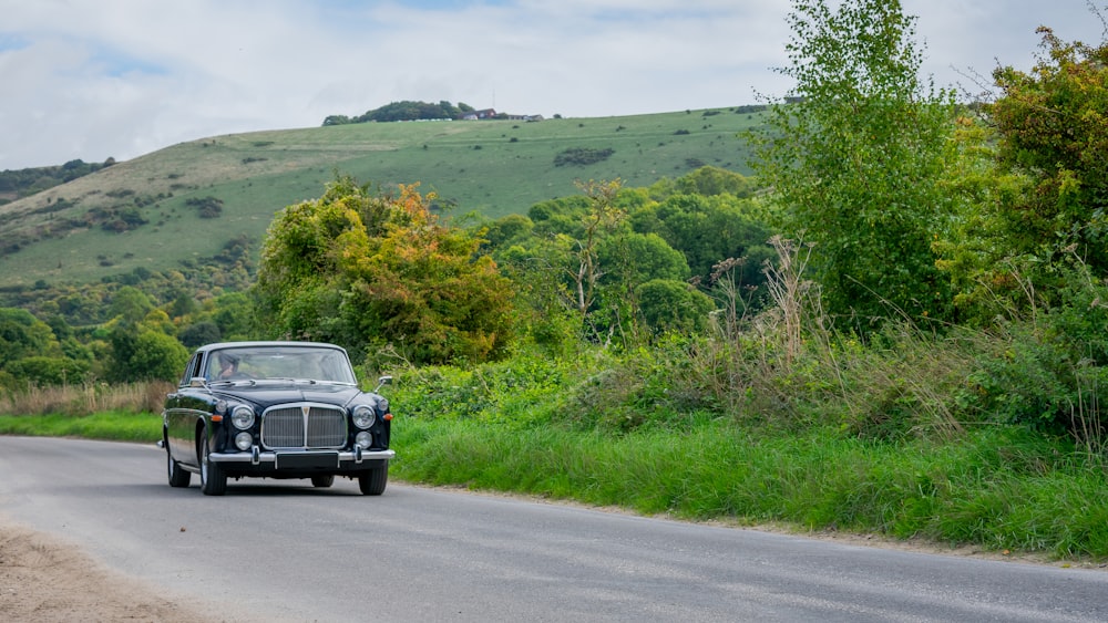 a vintage car driving down a country road