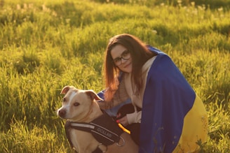 A veteran smiling warmly while playing fetch with their assistance dog on a grassy field.