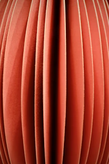 Close-up of layered topographic contours in warm off-white and terracotta on a dark background