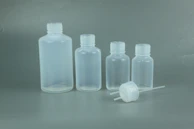 Various sizes of transparent plastic bottles displayed on a wooden table with soft lighting.