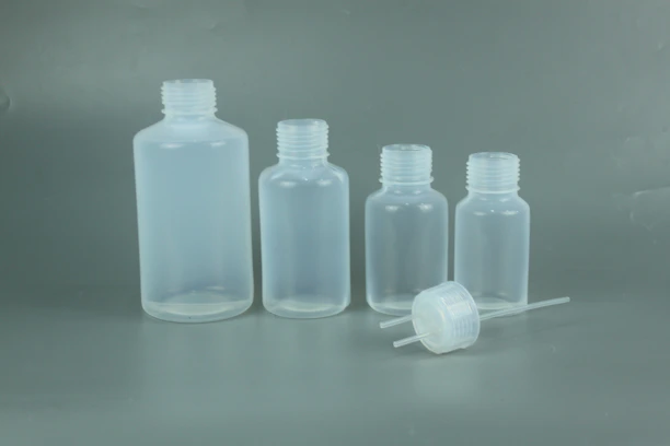 Close-up of shiny polypropylene bottles and pharmaceutical droppers lined up on a production conveyor.