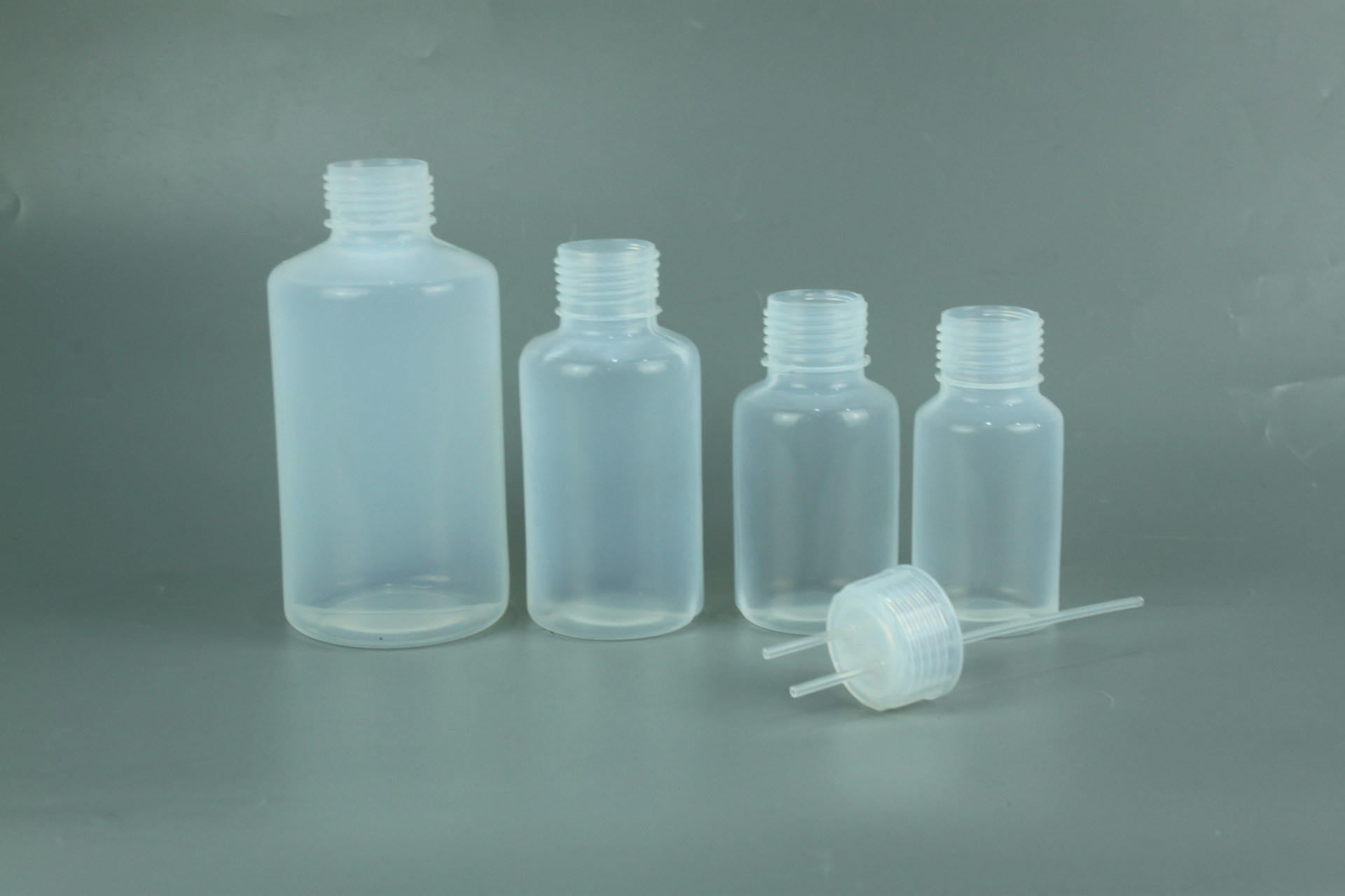 An array of Mist Pro bottles in 500 ml, 1 liter, and 4 liter sizes arranged neatly on a white surface with a subtle teal gradient backdrop.