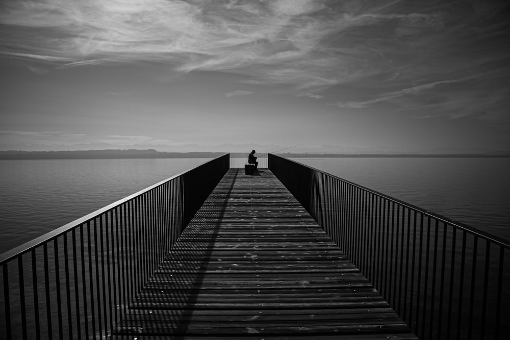 a person sitting on a pier looking out at the water