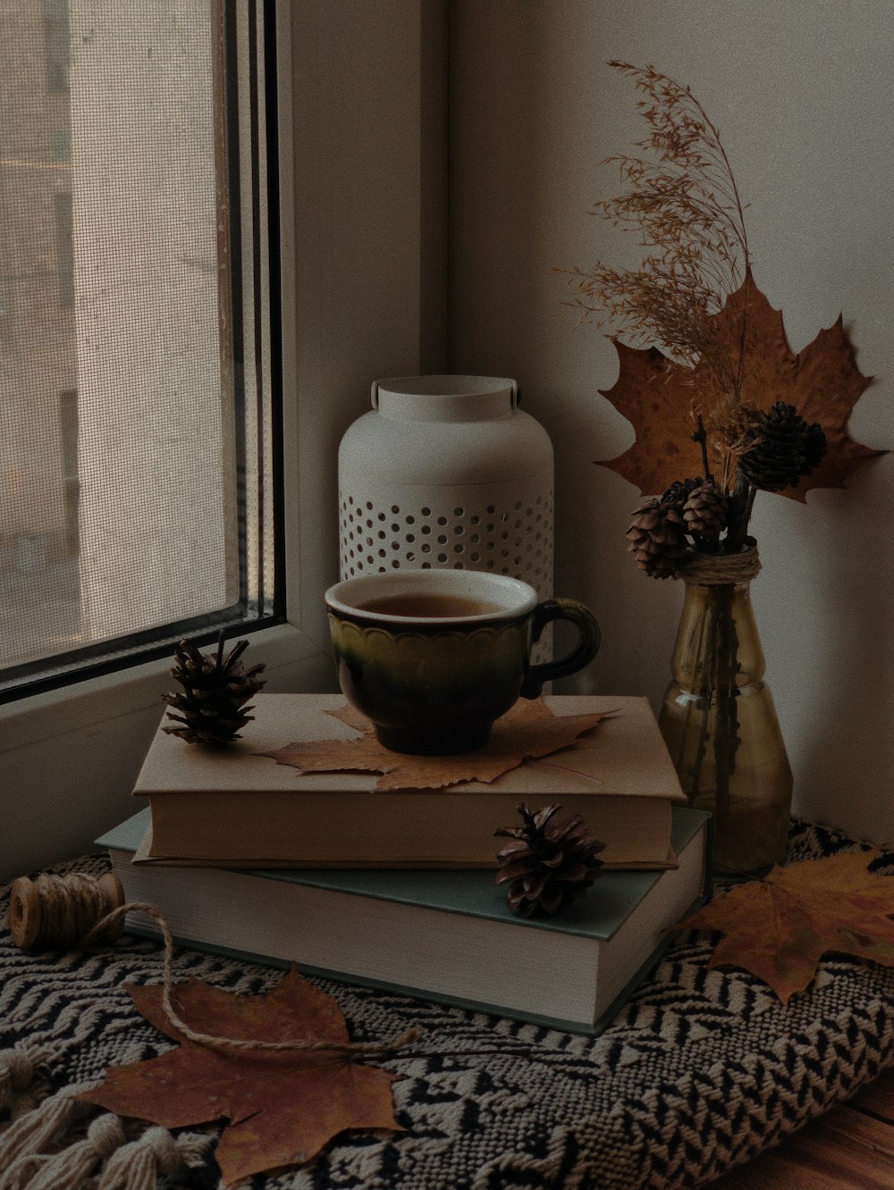 a stack of books sitting on top of a table next to a vase