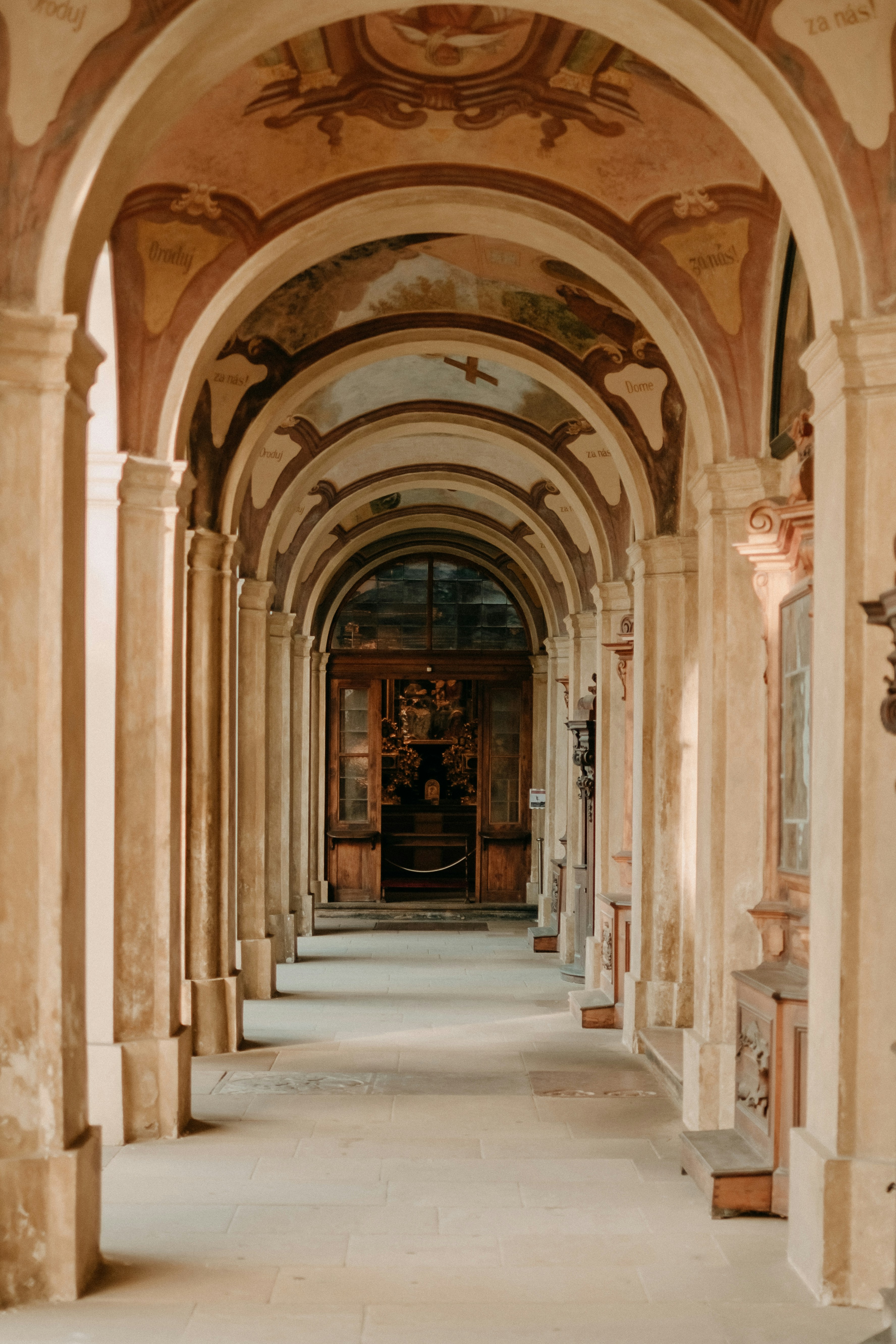a long hallway with arches and paintings on the walls