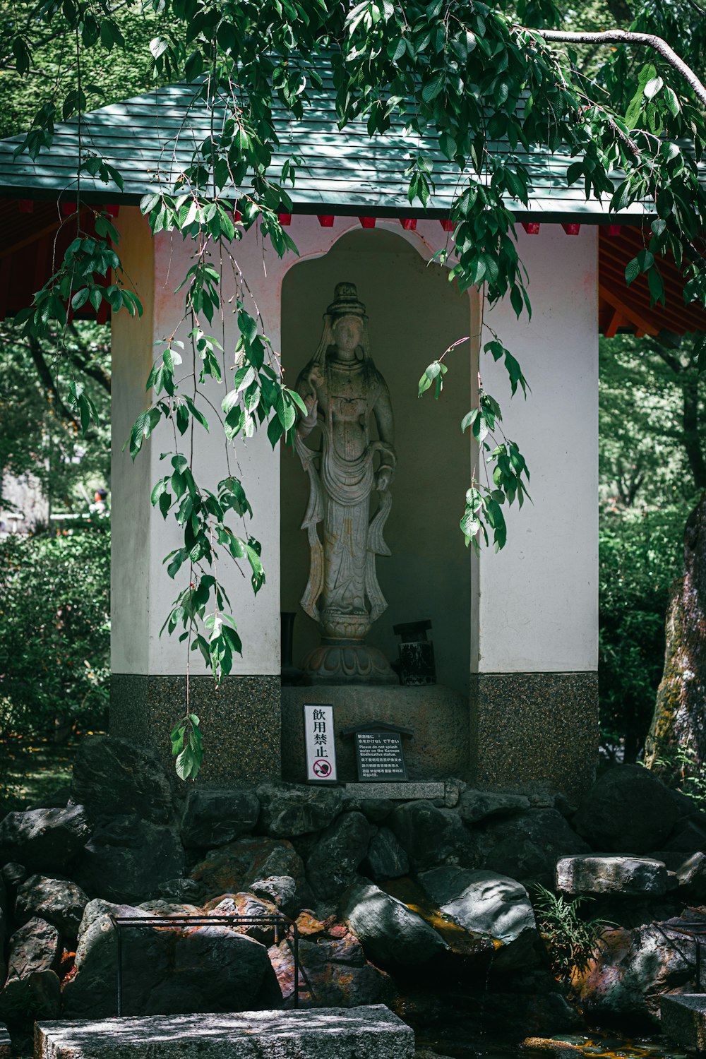 a statue of a person in a shrine surrounded by rocks