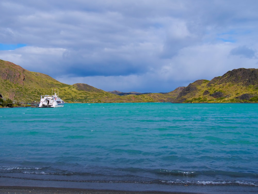 a boat in the middle of a lake with mountains in the background