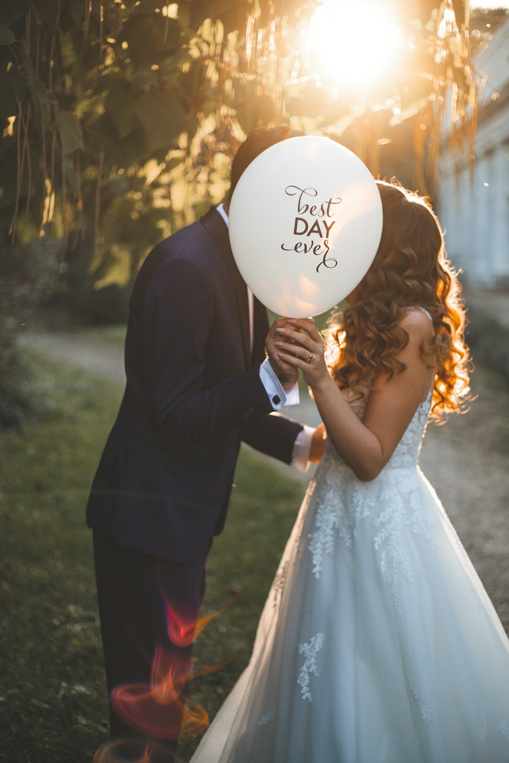 a bride and groom holding a white balloon that says best day ever