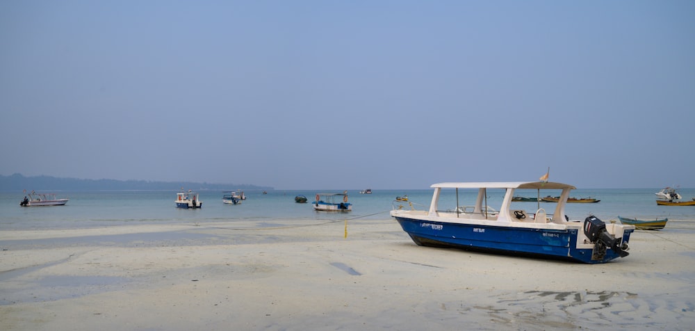 a blue and white boat sitting on top of a sandy beach
