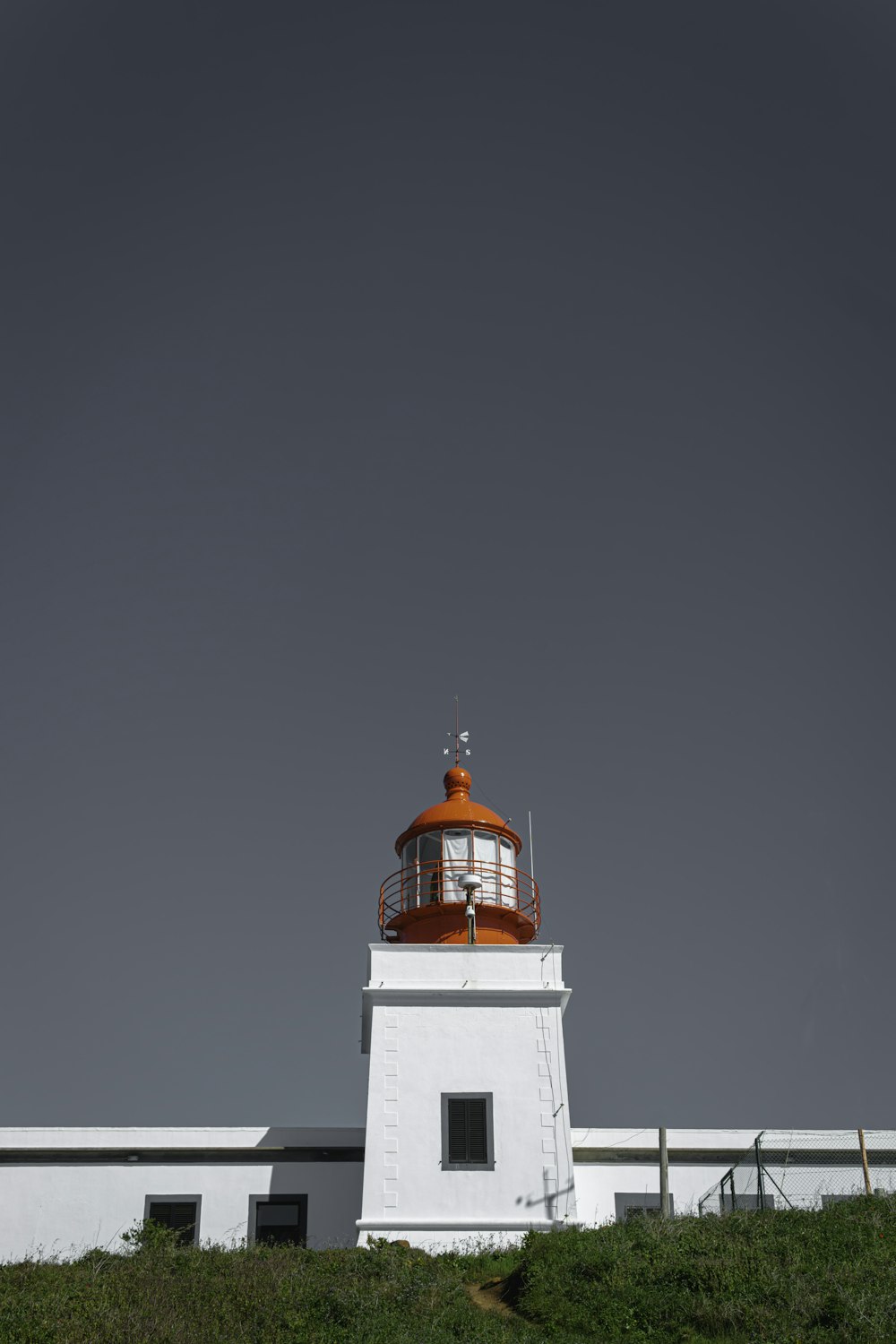 a white lighthouse with a red top on top of a hill