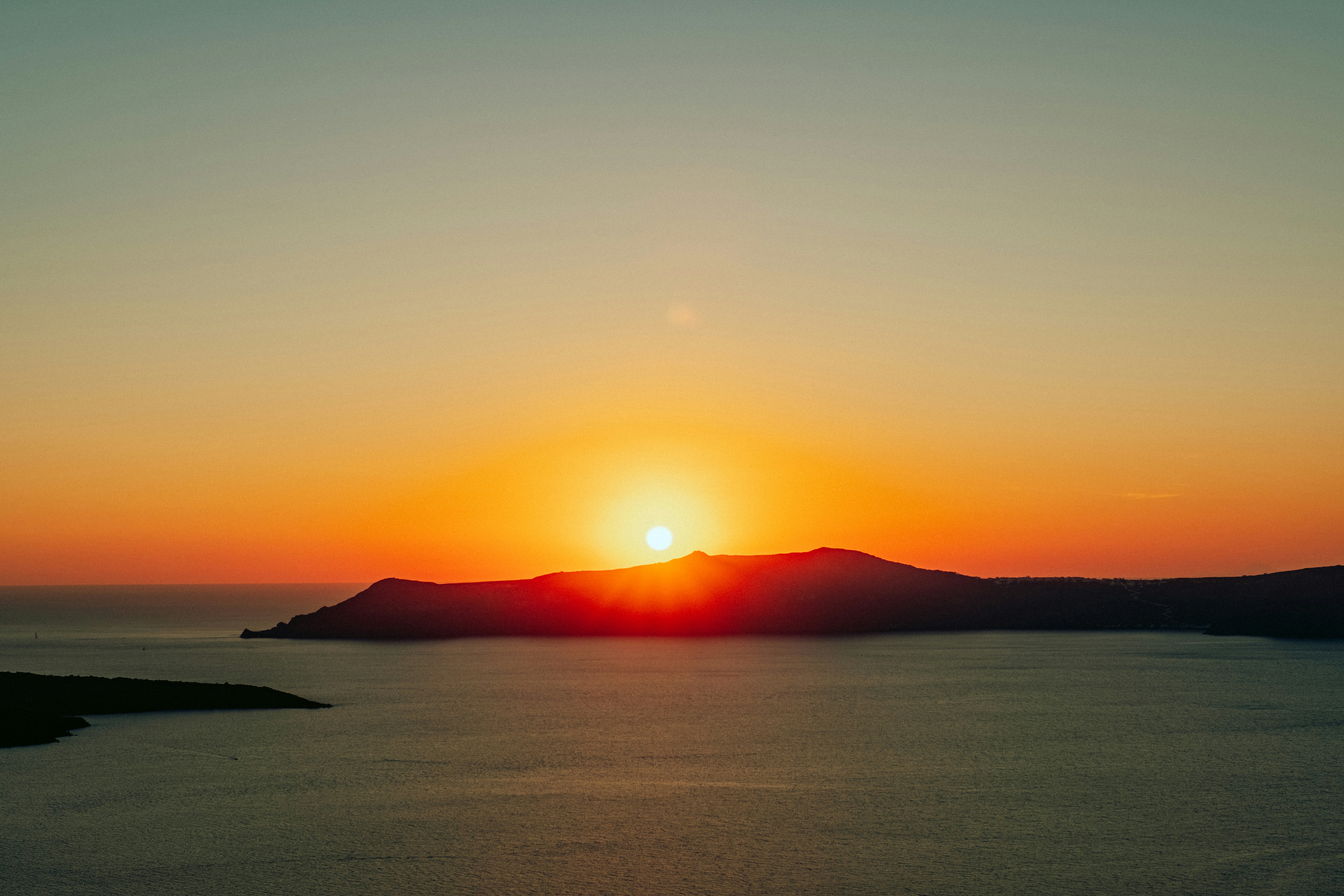 the sun is setting over a body of water, Sunset in Santorini, Greece.