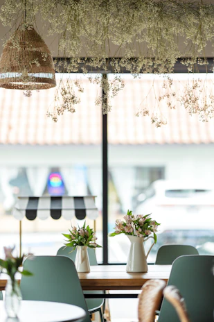 A cozy home setting featuring a wooden flower arrangement on a rustic wooden table beside a window.