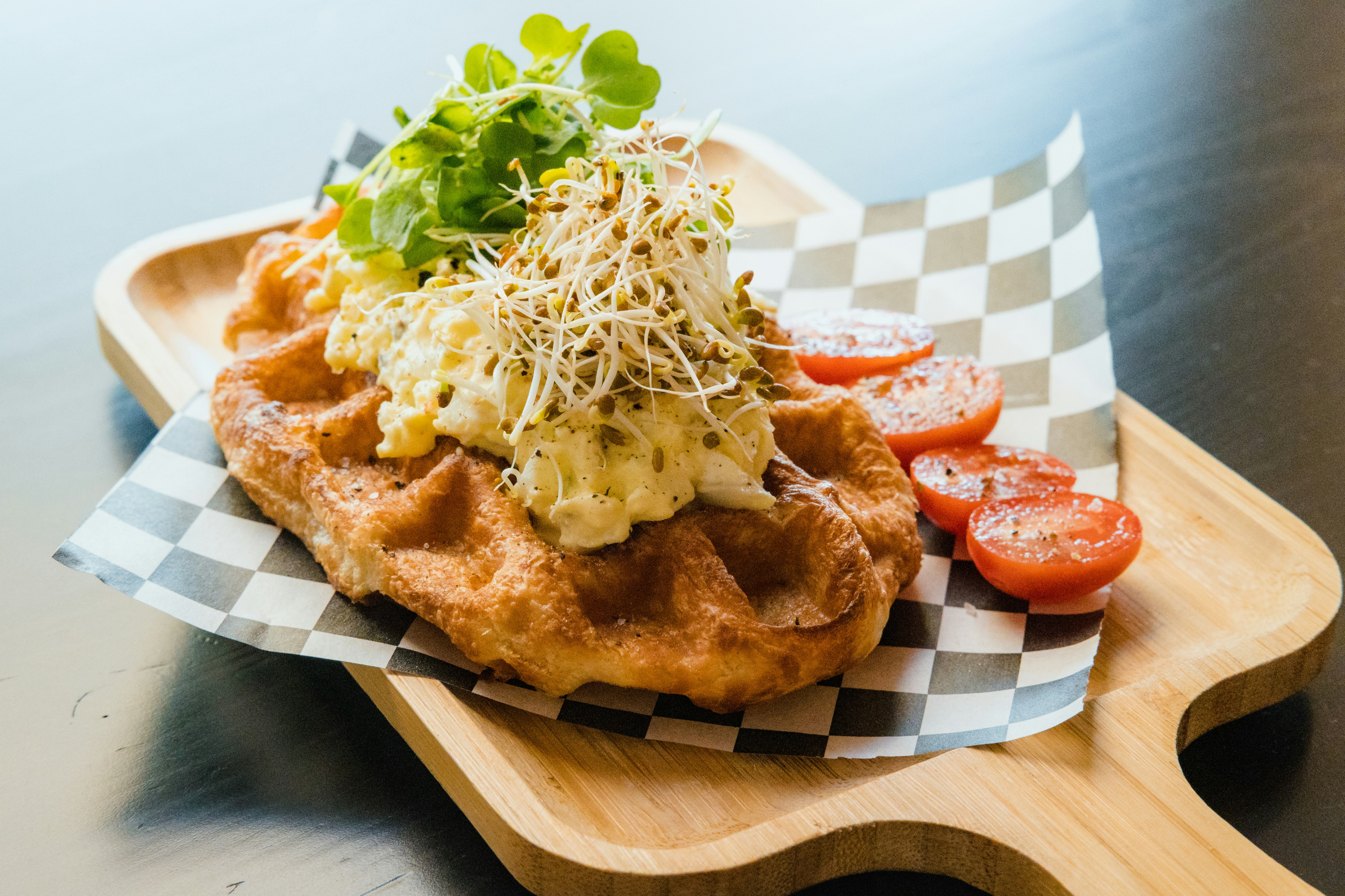 Waffle topped with scrambled egg and sprouts