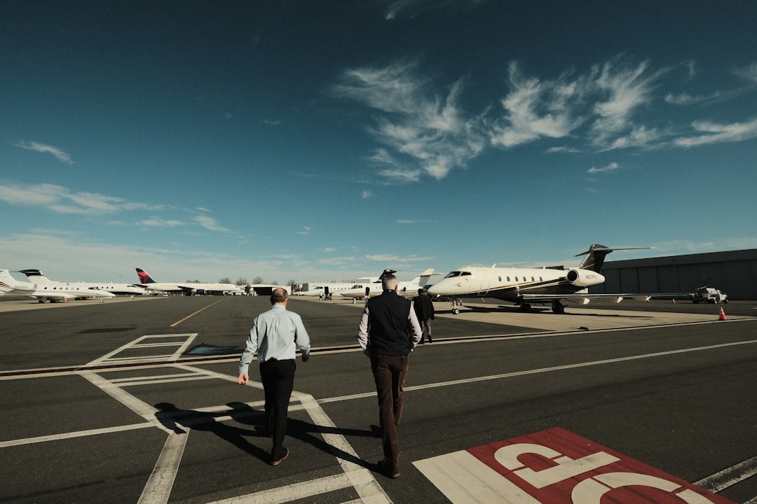 a couple of men walking across an airport tarmac,